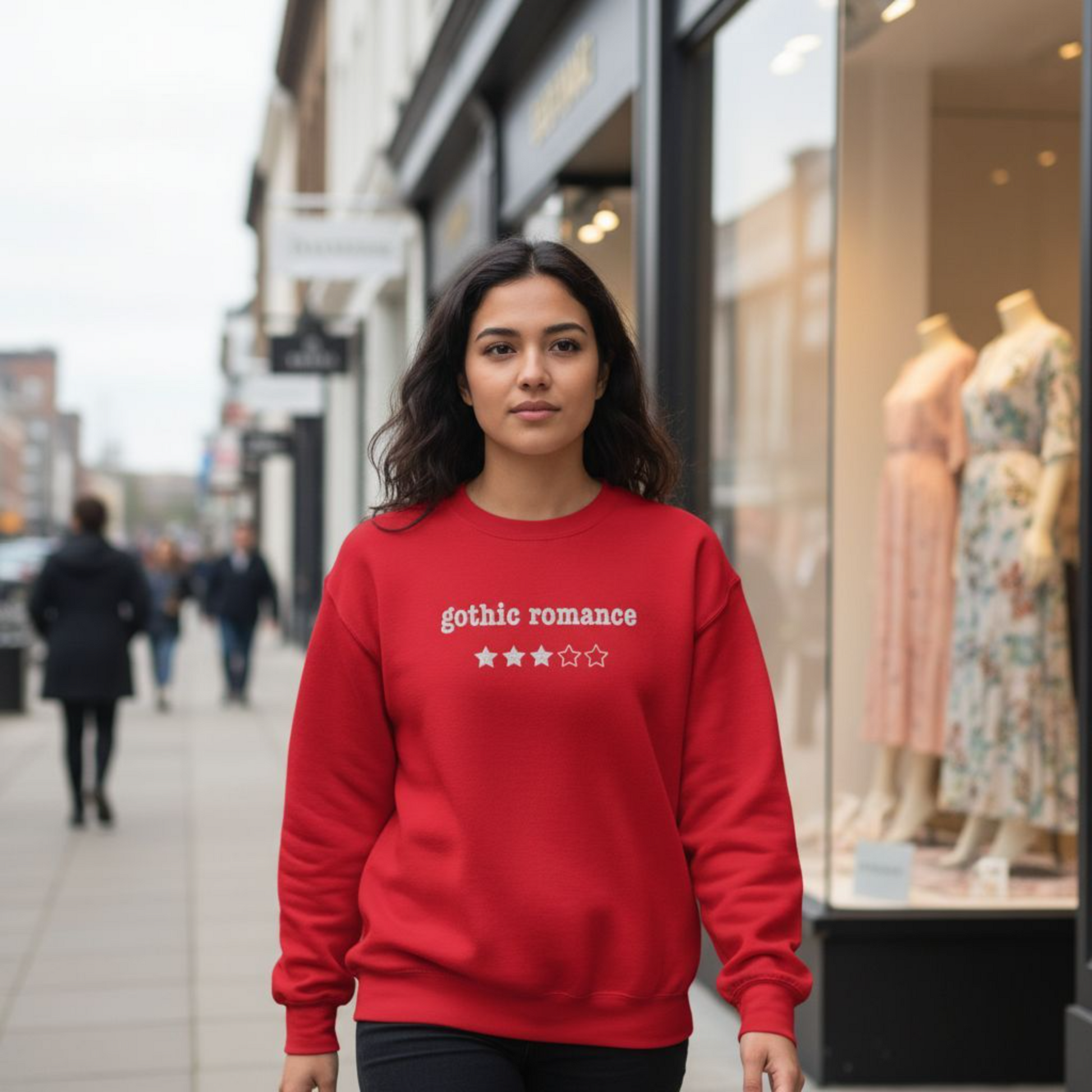 Woman wearing a red sweatshirt with 'gothic romance' embroidered text on a city street.